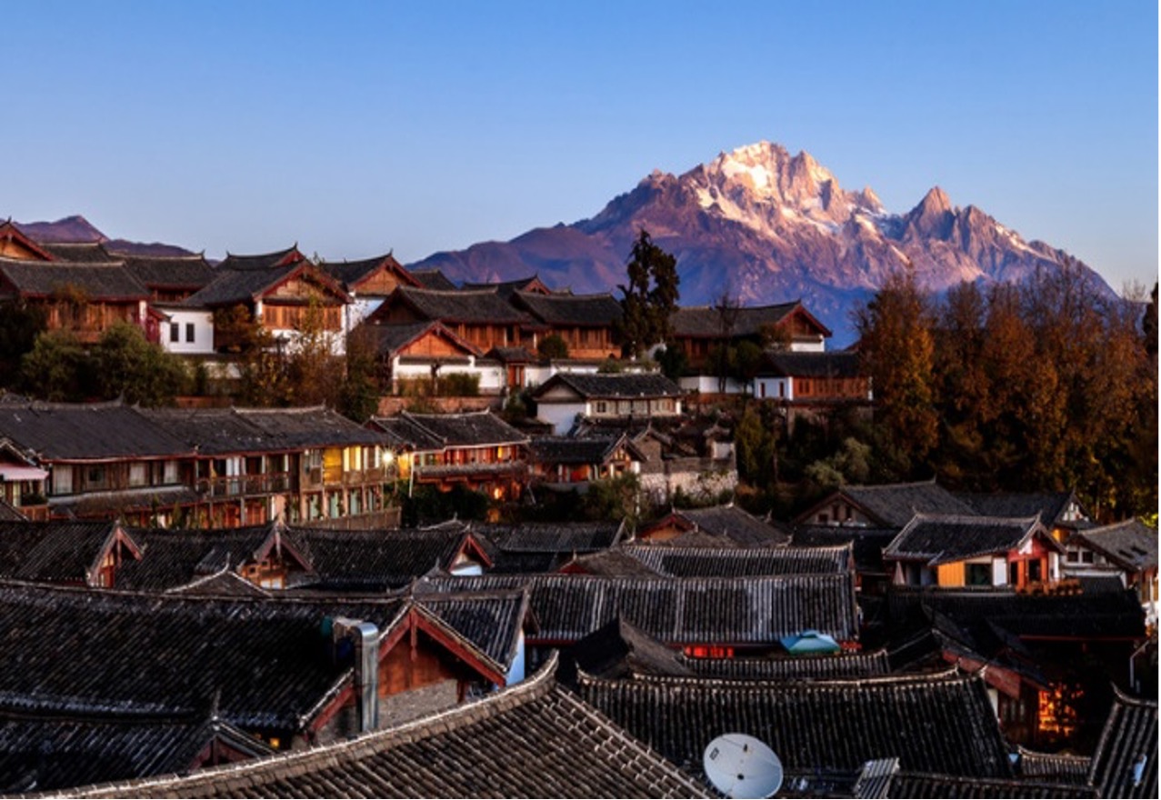 Oude stad met grijze pannendaken en de besneeuwde Jade Dragon berg op de achtergrond