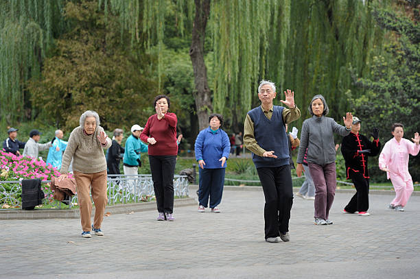Groep senioren oefent tai chi in een park met treurwilgen