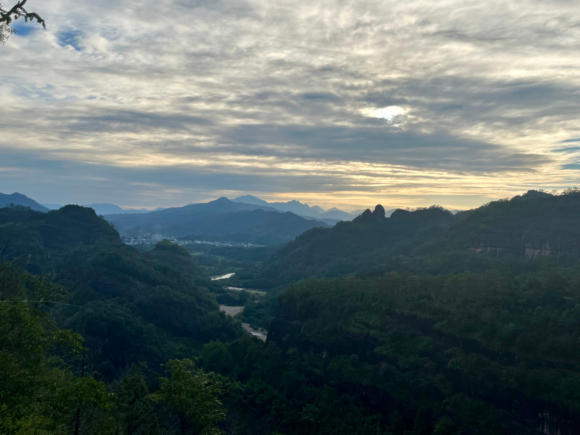 Uitzicht over een groen bergdal met een kronkelende rivier, gezien vanuit de lodge in Wumu